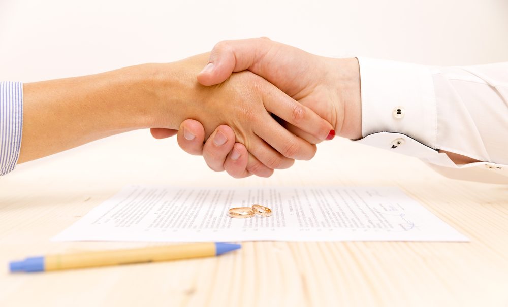 man and woman shaking hands after signing a prenuptial agreement