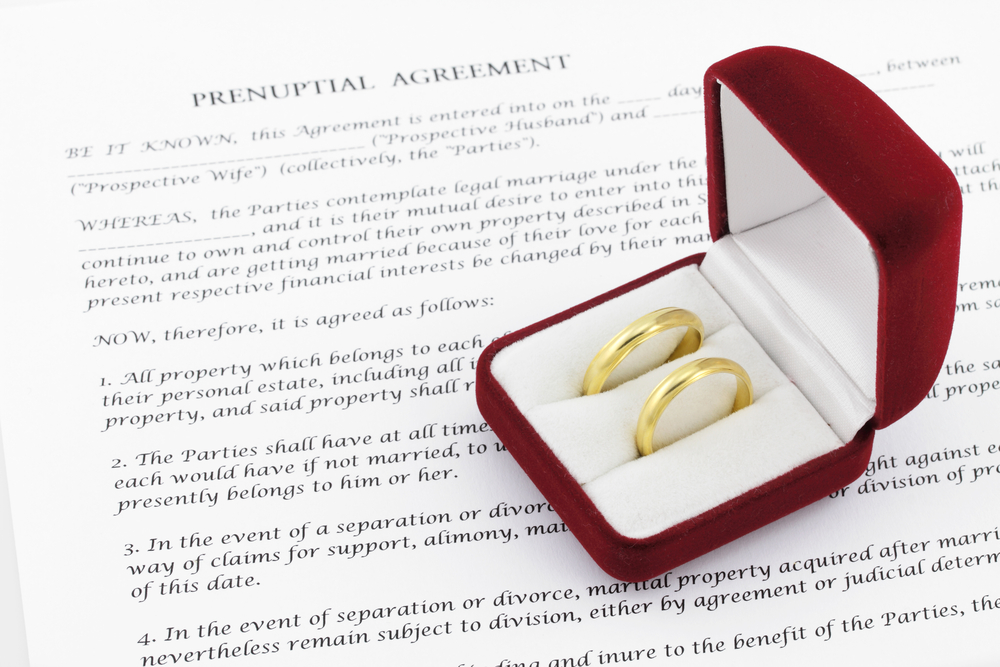 two gold wedding rings on top of a prenuptial agreement contract